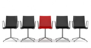 red office chair among black chairs isolated on white background